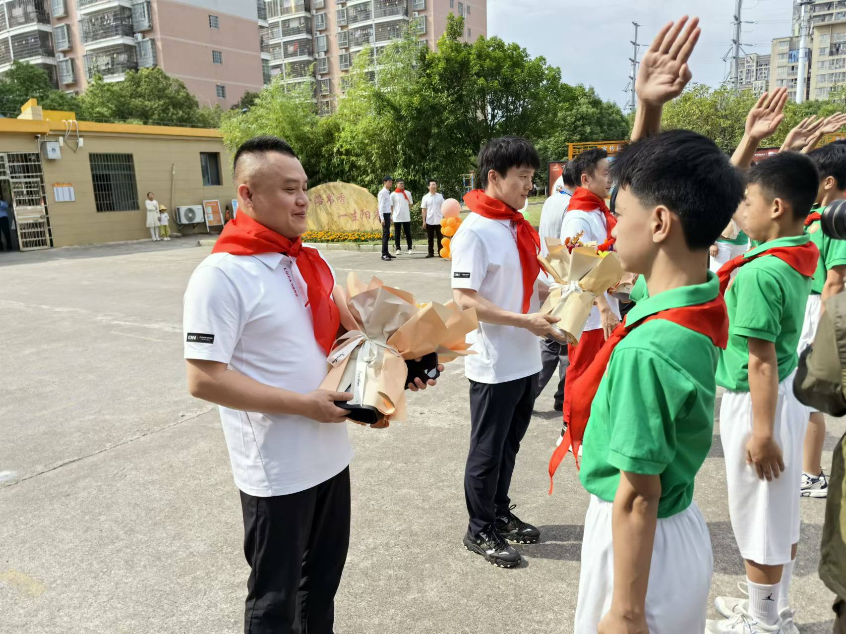 瑞金金穗学校学生为彭勃（左一）等奥运冠军佩戴红领巾、赠送鲜花。人民网记者杨磊摄